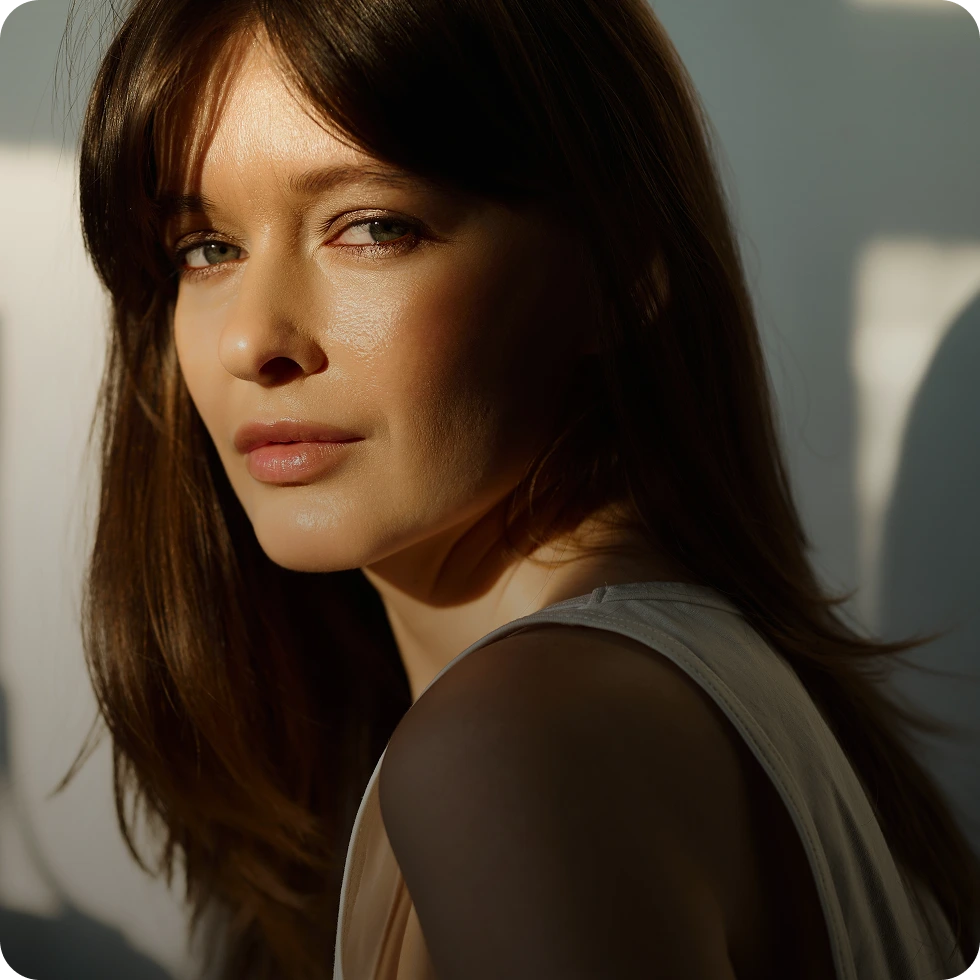 Woman with clear skin looking over her shoulder in natural sunlight